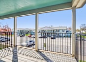 Thumbnail 9 of 35 - A view from a covered walkway looking out to a parking lot and buildings.