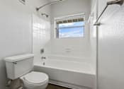 Thumbnail 18 of 61 - A white bathroom with a toilet, tub, and window.