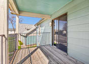 Thumbnail 16 of 35 - A wooden deck with a metal railing and a sliding glass door leading to a pool.