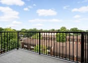 Thumbnail 11 of 41 - A balcony with a black railing overlooks a green landscape and buildings.