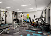 Thumbnail 34 of 41 - A gym with a variety of equipment including a treadmill, weight bench and exercise balls.
