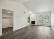 Thumbnail 7 of 21 - A large empty room with wood flooring and a fireplace.
