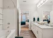 Thumbnail 25 of 64 - A bathroom with a tub, sink, and mirror.