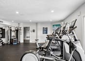 Thumbnail 51 of 61 - A gym with a row of stationary bikes and other exercise equipment.