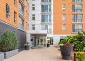 Thumbnail 3 of 45 - the entrance to an apartment building with a walkway and plants at Verge Apartments in St. Louis Park, MN