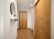 Thumbnail 28 of 45 - a hallway with a wooden door and a mirror on the wall at Verge Apartments in St. Louis Park, MN
