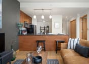 Thumbnail 30 of 45 - a living room with a couch and a kitchen with a bar at Verge Apartments in St. Louis Park, MN