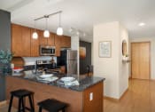 Thumbnail 34 of 45 - a kitchen with a granite counter top and a stainless steel refrigerator at Verge Apartments in St. Louis Park, MN