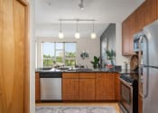 Thumbnail 32 of 45 - a kitchen with wooden cabinets and stainless steel appliances and a window at Verge Apartments in St. Louis Park, MN