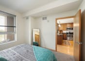 Thumbnail 43 of 45 - a bedroom with a large window and a door to a kitchen at Verge Apartments in St. Louis Park, MN