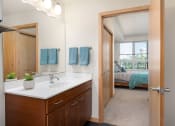 Thumbnail 44 of 45 - a bathroom with a mirror and a sink and a door to a bedroom at Verge Apartments in St. Louis Park, MN