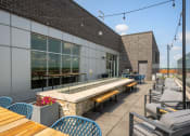 Thumbnail 14 of 45 - a patio with tables and chairs and a building with large windows at Verge Apartments in St. Louis Park, MN