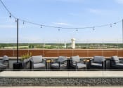 Thumbnail 18 of 45 - a rooftop patio with chairs and tables and a view of the city at Verge Apartments in St. Louis Park, MN