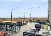 Thumbnail 16 of 45 - a rooftop patio with tables and chairs and a view of the city at Verge Apartments in St. Louis Park, MN