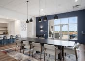 Thumbnail 10 of 45 - a dining room with a black table and chairs and a kitchen with a large window at Verge Apartments in St. Louis Park, MN