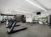 Thumbnail 22 of 45 - a gym with cardio equipment and weights in a building with white ceilings at Verge Apartments in St. Louis Park, MN