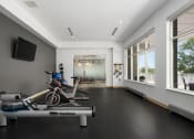 Thumbnail 23 of 45 - a workout room with a bike and other exercise equipment in a building with large windows at Verge Apartments in St. Louis Park, MN