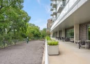 Thumbnail 25 of 45 - the terrace of a building with tables and chairs and trees at Verge Apartments in St. Louis Park, MN
