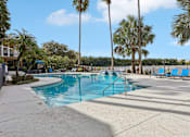 Thumbnail 56 of 61 - A swimming pool surrounded by palm trees and blue lounge chairs.