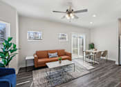 Thumbnail 7 of 16 - Four Bedroom Townhomes In Blue Springs, MO - Chapman Ridge Townhomes - A Living Room With Tan Leather Sofa, Large Window, Glass Sliding Doors, Ceiling Fan, And A Sleek Table.