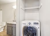 Thumbnail 23 of 35 - A white washing machine in a laundry room.