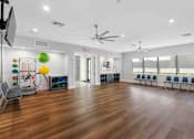 Thumbnail 23 of 35 - a large room with hardwood floors and a gym with chairs and a large window