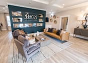 Thumbnail 29 of 64 - A living room with a grey couch and a coffee table in front of a wall with a sign that says "The Haven at Regent Park".