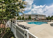 Thumbnail 43 of 64 - A pool surrounded by a white fence with trees in the foreground.