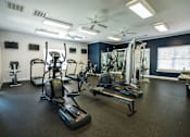 Thumbnail 34 of 64 - A spacious gym with a variety of equipment including treadmills, elliptical machines, and a weight bench.