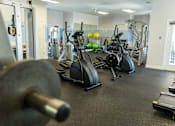 Thumbnail 33 of 64 - A gym with a variety of equipment including weights and cardio machines.