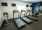 Thumbnail 32 of 64 - A gym with treadmills, elliptical machines, and a stationary bike.