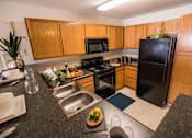 Thumbnail 22 of 64 - A kitchen with wooden cabinets and black appliances.
