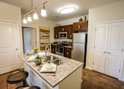 Thumbnail 1 of 64 - A kitchen with a granite countertop and a refrigerator.