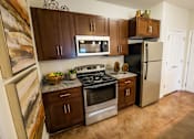 Thumbnail 12 of 64 - A kitchen with brown cabinets and a black refrigerator.