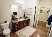 Thumbnail 8 of 64 - A bathroom with a white toilet, a sink with a brown counter, and a white rug.