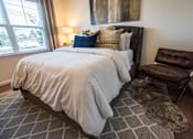 Thumbnail 5 of 64 - A bedroom with a large bed and a brown leather chair.