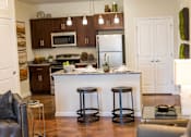 Thumbnail 3 of 64 - A kitchen with a white island and black stools.