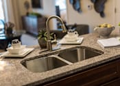 Thumbnail 2 of 64 - A kitchen sink with a silver faucet and a plant on the counter.