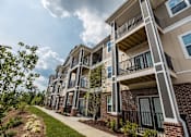Thumbnail 63 of 64 - A row of apartment buildings with balconies and black railings.