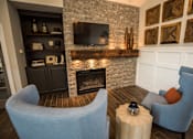 Thumbnail 41 of 64 - A living room with a stone fireplace and a television above it.