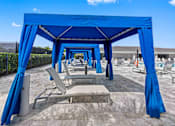 Thumbnail 24 of 35 - a row of blue shade structures with tables and chairs