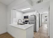 Thumbnail 23 of 61 - A modern kitchen with white countertops and stainless steel appliances.