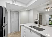 Thumbnail 25 of 61 - A kitchen with a black refrigerator, white cabinets, and a sink.