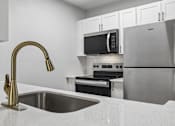 Thumbnail 24 of 61 - A kitchen with a sink, refrigerator, and microwave.