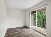 Thumbnail 8 of 21 - A room with a sliding glass door leading to a balcony.