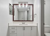 Thumbnail 28 of 61 - A bathroom with a sink, mirror, and cabinets.