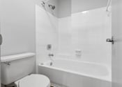 Thumbnail 29 of 61 - A white bathroom with a toilet, bathtub, and shower.