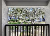 Thumbnail 33 of 61 - A view from a balcony looking out at a tree and a street.