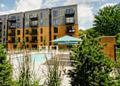 Thumbnail 1 of 79 - A large apartment complex with a pool in the foreground.