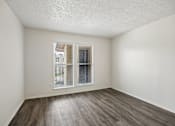 Thumbnail 11 of 21 - A room with a window and wooden flooring.